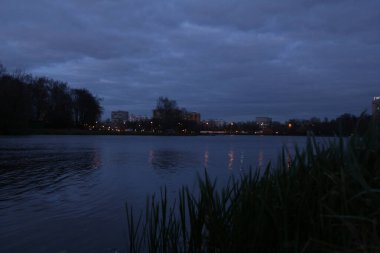 Alacakaranlıkta göl kenarındaki uzak şehir ışıkları