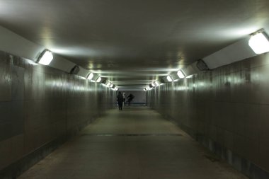 Yeraltı yaya geçidinden çıkan insanların siluetleri.