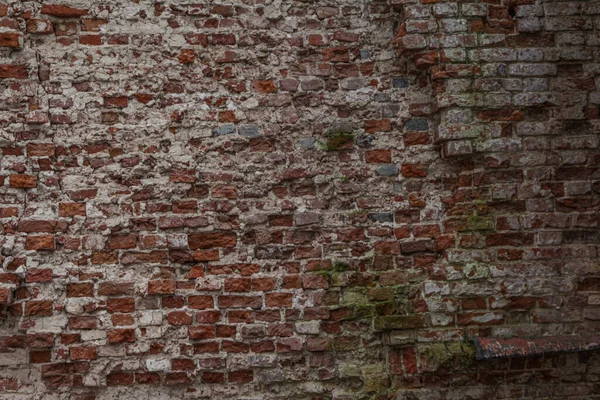 The wall of a red brick house, partially crumbling from age