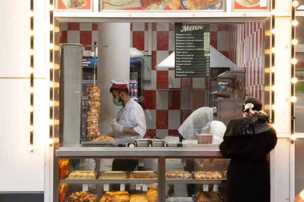 Moskova, Rusya, 30 Kasım 2020: Fırında pişmiş mallar, çörekler, sandviçler ve shawarma ile mağaza penceresi. Aşçı, mağazanın yanında duran bir kadın müşteriyi paketliyor.