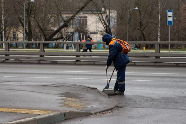 Moskova, Rusya, 30 Kasım 2020: üniformalı kamu görevlisi kaldırımı süpürüyor