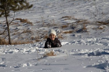 Küçük bir çocuk kar yığınına battı ve kurtulmaya çalışıyor. 