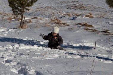 Küçük bir çocuk kar yığınına battı ve kurtulmaya çalışıyor. 