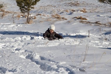 Küçük bir çocuk kar yığınına battı ve kurtulmaya çalışıyor. 