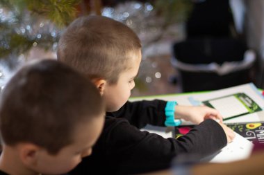 Çocuklar masada oturup birlikte oynar ve müteahhitten rakamlar toplarlar.