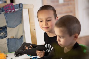 Çocuklar masada oturup birlikte oynar ve müteahhitten rakamlar toplarlar.