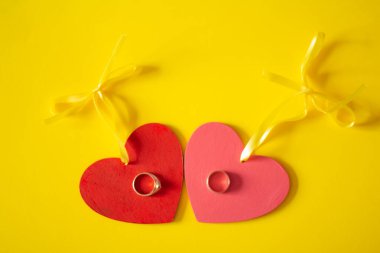 Sarı arka planda kırmızı ve pembe kalpler ve altın alyanslar var: Sevgililer Günü ve Düğün Günü için illüstrasyon