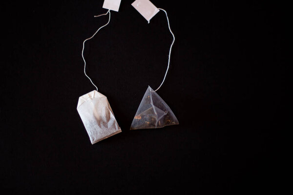 На черном фоне чайный пакетик и чайная пирамида 