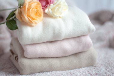 Bir yığın kaşmir kazak pembe kabarık bir battaniyenin üzerinde, yumuşacık güllerin yanında. 