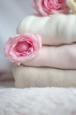 Bir yığın kaşmir kazak pembe kabarık bir battaniyenin üzerinde, yumuşacık güllerin yanında. 