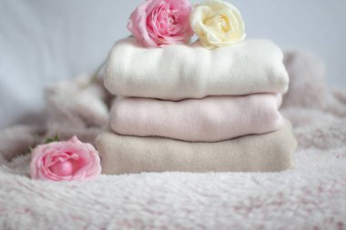 Bir yığın kaşmir kazak pembe kabarık bir battaniyenin üzerinde, yumuşacık güllerin yanında. 