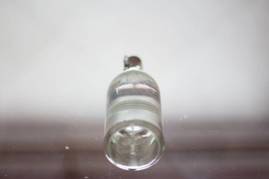 Cam şişe şeffaf cam üzerinde duruyor. 