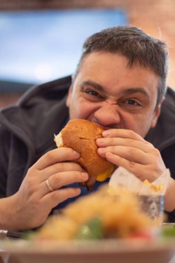 Kafede hamburger yiyen bir adam.