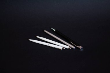 Siyah arka planda beyaz ve siyah tükenmez kalemler 