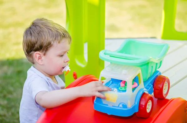 Lindo niño juega con coche de juguete en el parque — Foto de Stock