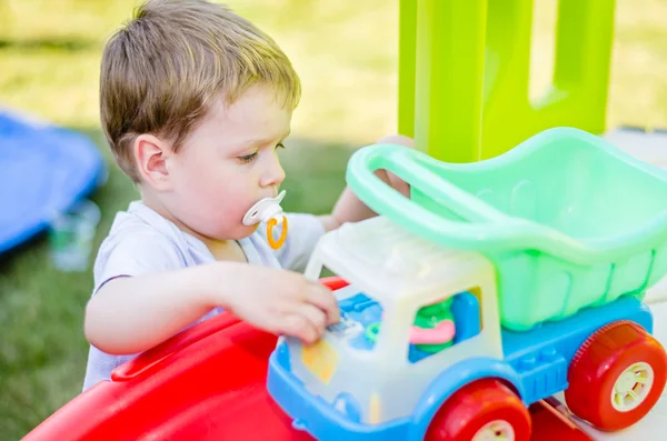 Schattige kleine jongen speelt met speelgoedauto bij park Stockfoto