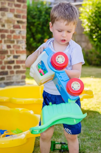 Cute little boy plays with toy car at park — Stock Photo, Image