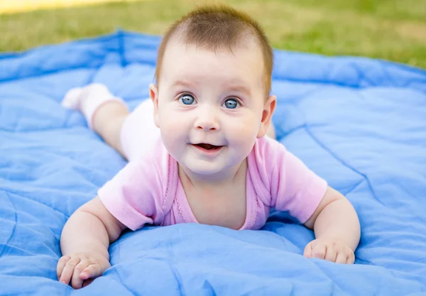 Schattig klein babymeisje is glimlachend en spelen op gras — Stockfoto