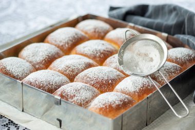 Üstünde pudra şekeri olan tatlı ekmek ruloları.