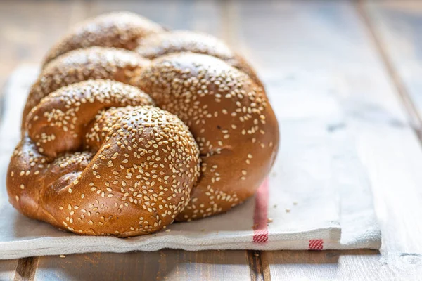 Tradiční židovský sladký chléb Challah pro šabat na bílém textilu na dřevěném stole, zblízka. — Stock fotografie