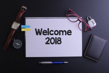 Not defteriyle seyahat kavramı. Pasaport, saat, kalem ve saat ile 2018 'e hoş geldiniz.