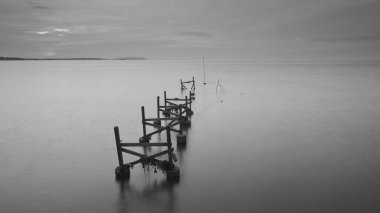 Pastel günbatımında eski kırık iskelenin uzun pozu.