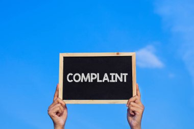 COMPLAINT / Man mavi gökyüzü arka planında küçük bir karatahta tutuyor