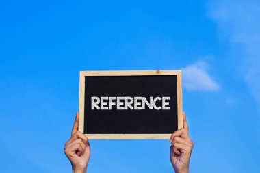 REFERENCE / Man mavi gökyüzü arka planında küçük bir karatahta tutuyor