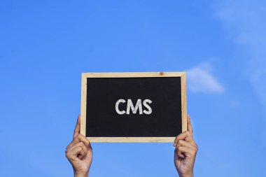 CMS / Man mavi arkaplanda küçük bir karatahta tutuyor