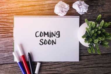 Yakında Notepad ve ahşap arka planda yeşil bitki ile geliyor.