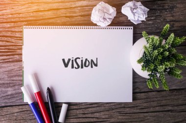 Notepad ve ahşap arka planda yeşil bitki ile vizyon kelime