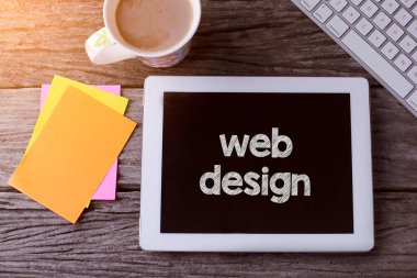 Web tasarımı tableti ve ahşap arka planda bir fincan kahve.