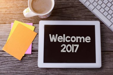 2017 numaralı tablet ve ahşap arka planda bir fincan kahve.