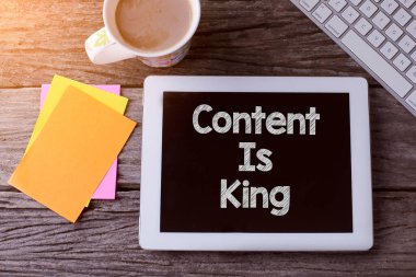 İçerikli tablet kral ve tahta arka planda bir fincan kahve.