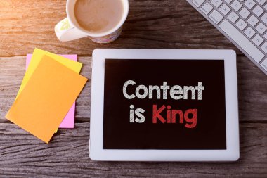 İçerikli tablet kral ve tahta arka planda bir fincan kahve.