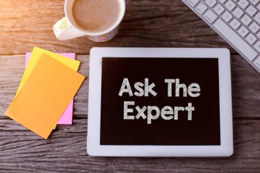 Expert 'a Sor tableti ve tahta arka planda bir fincan kahve.