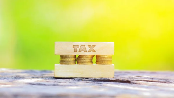ビジネスコンセプト Tax Word 浅いDof緑の背景に木製の棒で積み上げられた黄金のコイン — ストック写真