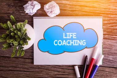 Not Defteri ve ahşap arka planda yeşil bitkilerle yaşam koçluğu kelimesi