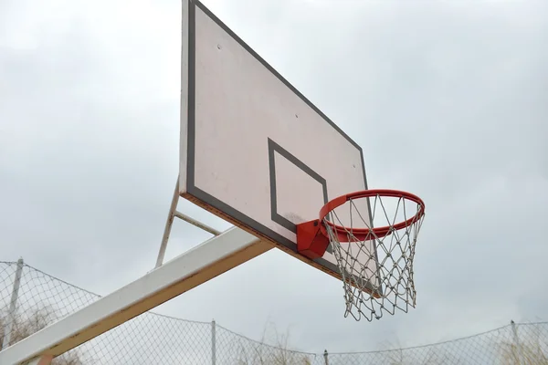 Tablero de baloncesto bajo el cielo nublado en un patio de la escuela. Concepto de k — Foto de Stock