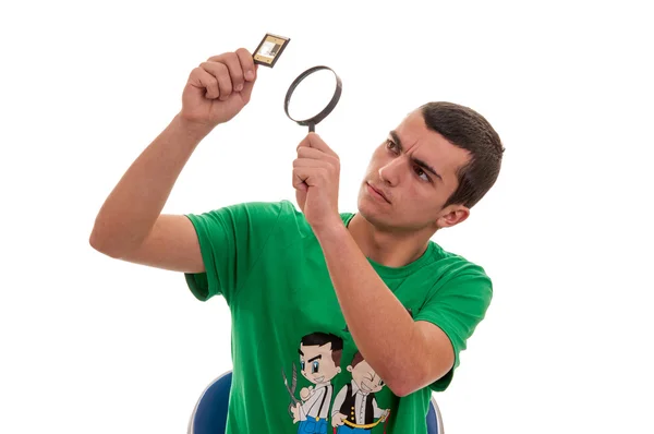 Young man looking with a magnifying glass at a photographic film — Stock Photo, Image