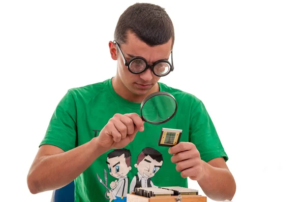 Young man looking with a magnifying glass at a photographic film — Stock Photo, Image