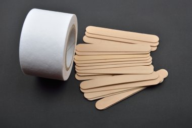Birçok tahta spatula ve balmumu depila için kağıt rulosunun resmi