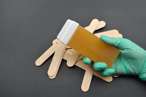 Rękę kosmetyczki z zielone rękawice trzymając rolki na rozpuszczalnymi w tłuszczu — Zdjęcie stockowe