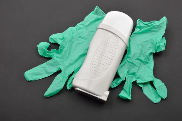 Зеленая перчатка и белый переносной рулон на эпиляторном восковом обогревателе — стоковое фото