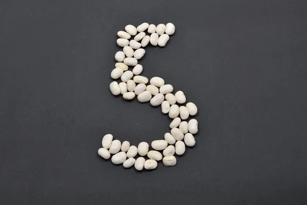 Number five made from white beans on black background. Food vega — Stock Photo, Image