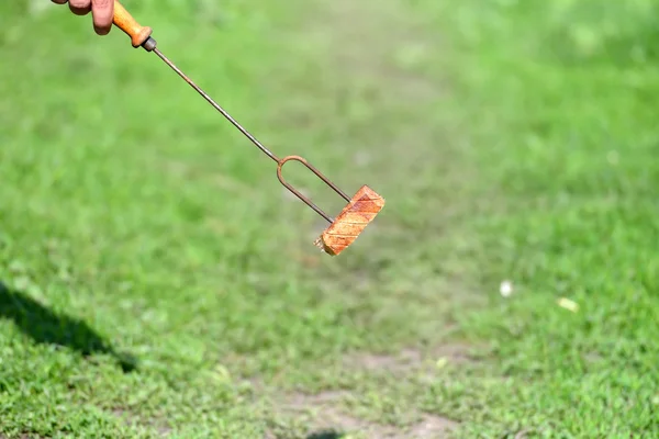 Hand van een persoon die houdt van een vork met een plakje spek voor bar — Stockfoto