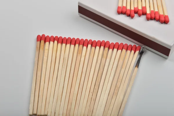 Many red head matches and one burned put straight in line near a — Stock Photo, Image