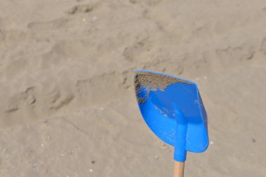 Plastik ahşap kuyruk mavi kürek kum üzerinde içinde çocuklar için bir 