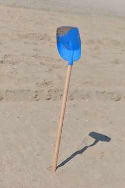 Plastik ahşap kuyruk mavi kürek kum üzerinde içinde çocuklar için bir 
