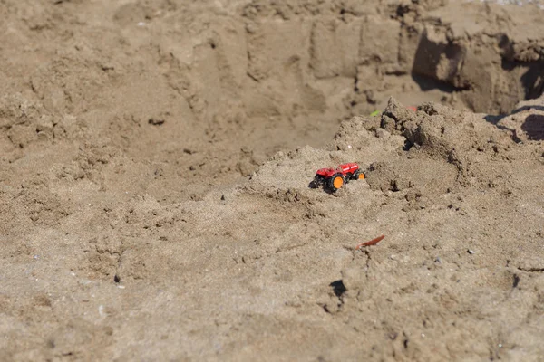 Piccolo trattore giocattolo in metallo rosso sulla spiaggia di sabbia bagnata. Estate vacati — Foto Stock